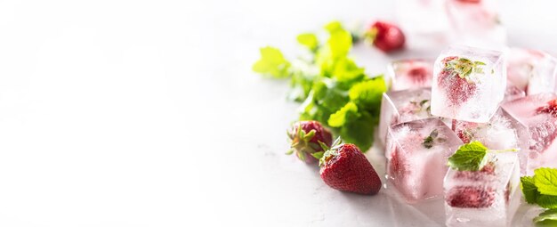 In Eiswürfeln eingefrorene Erdbeeren mit Melissa-Blätter-Banner mit Kopienraum