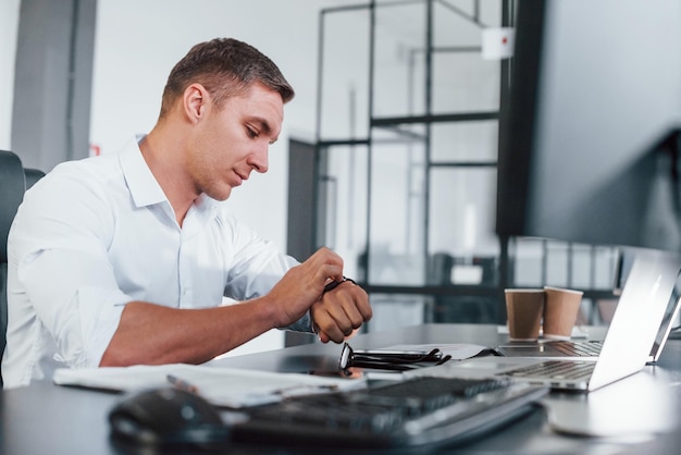 In formeller Kleidung Junge männliche Börsenmakler arbeiten drinnen im Büro Viele Displays