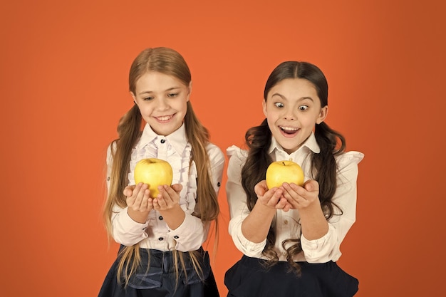 In Gesundheit wachsen Schulkinder mit gesundem Apfelsnack Kleine Mädchen, die einen Schulsnack einnehmen Kleine Mädchen, die natürliche Vitaminnahrung essen Nette Schulmädchen, die Äpfel halten Früchte sind reich an Vitaminen