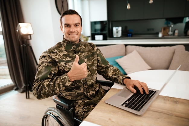 In Militäruniform sitzt er neben seinem Laptop