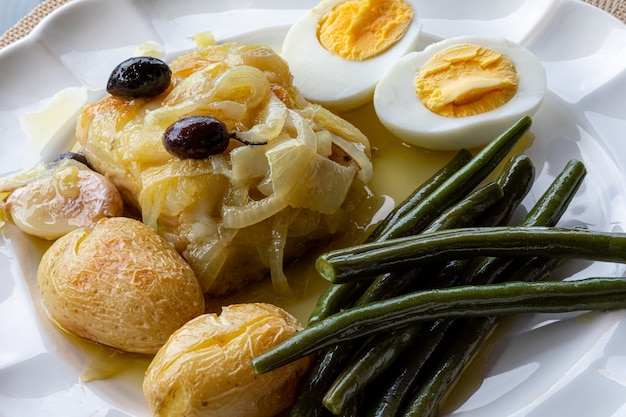 In Olivenöl gebackener Kabeljaufilet mit Kartoffeln, Brokkoli, gekochtem Ei und schwarzen Oliven. Typisches Gericht Portugals.