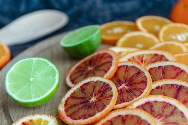 In runde Scheiben von mehrfarbigen Zitrusfrüchten, Orange, Limette und Blutorange schneiden. Tiefblau und Holz. Ein Urlaub voller Geschmack und Farbe. Nahansicht.