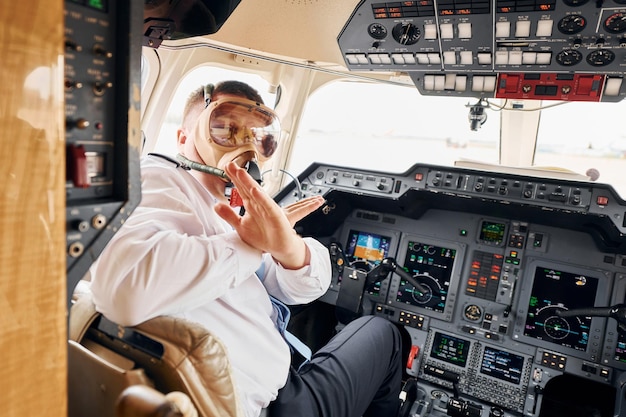 In Sauerstoffmaske sitzt der Pilot in formeller Kleidung im Cockpit und steuert das Flugzeug