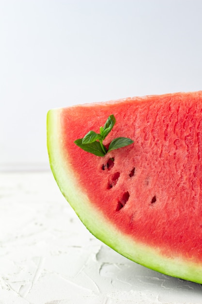 In Scheiben geschnitten von frischer roter reifer Wassermelone mit grünen Blättern der Minze auf Weiß