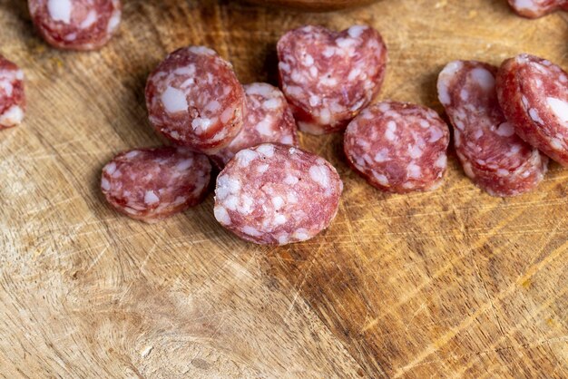 In Scheiben geschnittene dünne Wurst mit Speck auf einem Holzteller