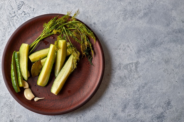 In Scheiben geschnittene gesalzene Gurken mit Knoblauch und Dill auf einer hellen Oberfläche