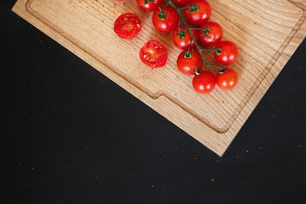 In Scheiben geschnittene Tomaten auf einem Holzbrett. Auf schwarzer Tafel. Schwarzer Hintergrund mit Kopienraum.