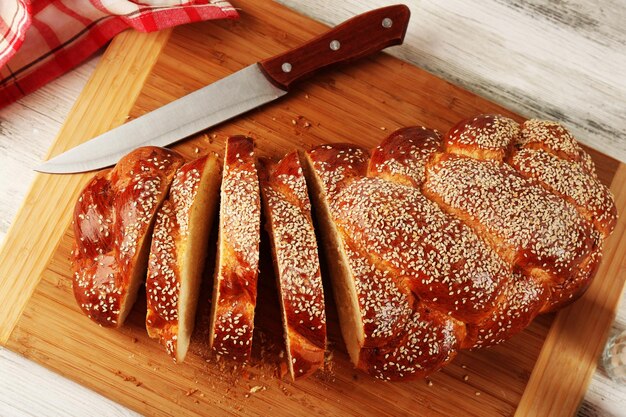 Foto in scheiben geschnittenes frisches brötchen auf schneidebrett auf holztisch aus nächster nähe