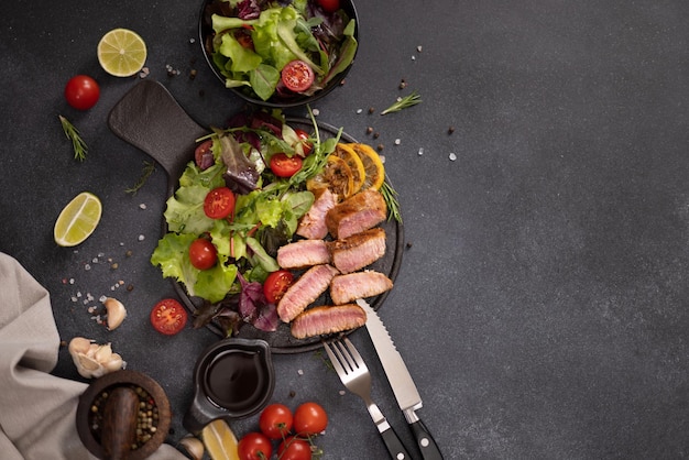 In Scheiben geschnittenes, gegrilltes Bio-Thunfischsteak auf schwarzem Keramikteller mit Salat auf einem Tisch