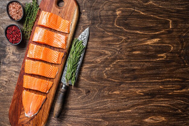 In Scheiben geschnittenes Lachsfilet rohes Fischfleisch mit Thymian und Rosmarin Holzhintergrund Draufsicht Kopierbereich