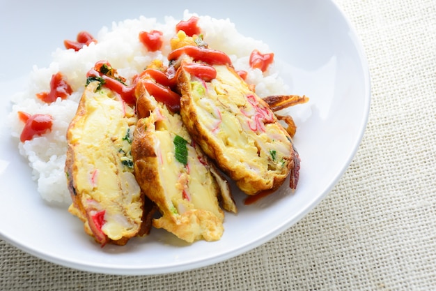 In Scheiben geschnittenes Omelett mit weichem Tofu, Krabbenstäbchen und Frühlingszwiebeln mit Reis auf Teller