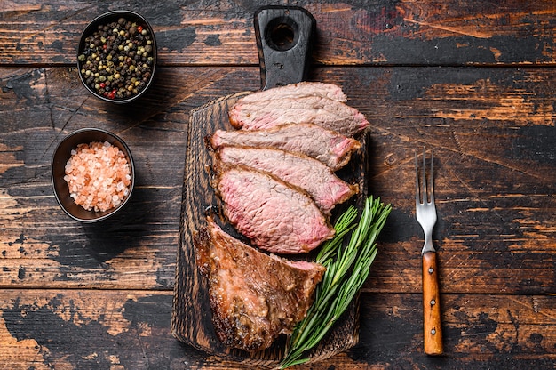 In Scheiben geschnittenes Roastbeef-Lendenstück Tri-Tip-Steak-Grill. Dunkler Holztisch. Draufsicht.