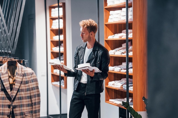 In schöner schwarzer Jacke Junger Mann im modernen Laden mit neuer Kleidung Elegante teure Kleidung für Männer