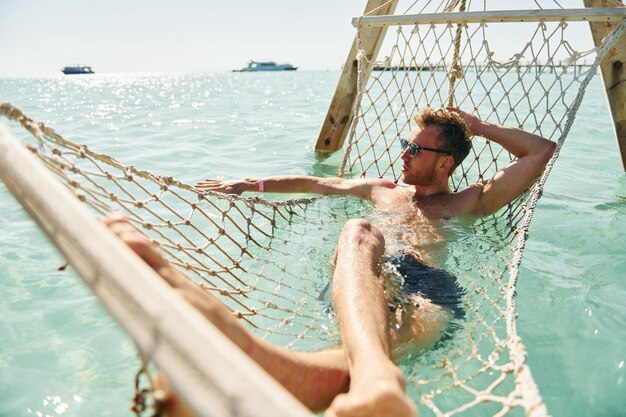 In Sonnenbrillen Junger europäischer Mann hat Urlaub und genießt Freizeit am Strand des Meeres