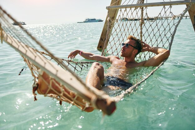 In Sonnenbrillen Junger europäischer Mann hat Urlaub und genießt Freizeit am Strand des Meeres