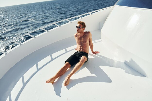 In Sonnenbrillen Junger männlicher Tourist ist auf der Yacht auf dem Meer Konzeption des Urlaubs