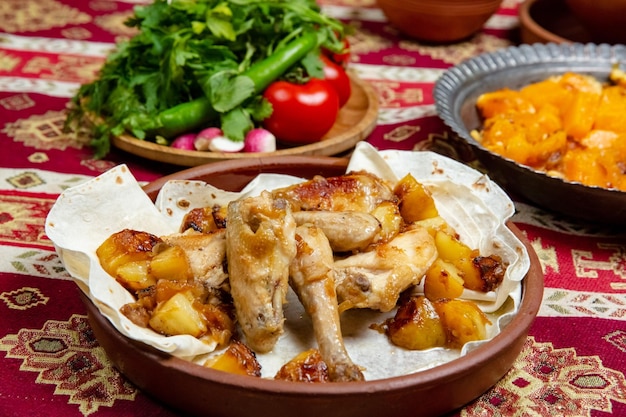 In Stücken gebackenes Hühnchen mit Kartoffeln und Zwiebeln auf einer Tonplatte