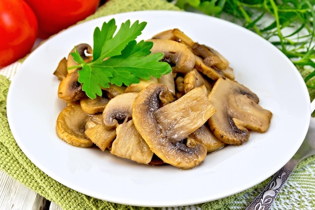 In Teller gebratene Champignons und Tomaten auf leichtem Brett