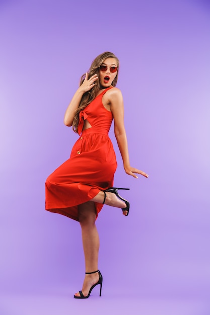 In voller Länge Porträt der Mode Brünette Frau trägt rotes Kleid und Sonnenbrille wundern sich