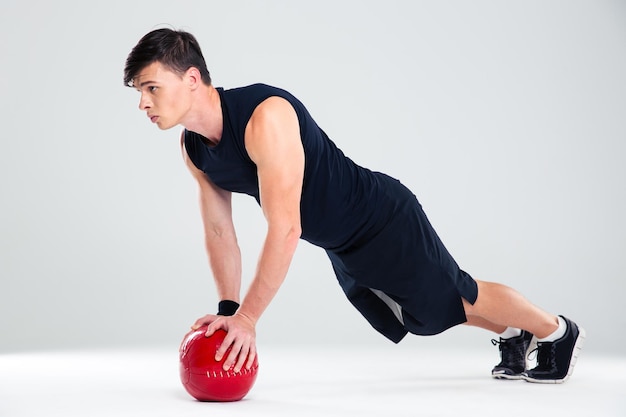 In voller Länge Portrait eines gutaussehenden Mannes Training mit Fitnessball isoliert