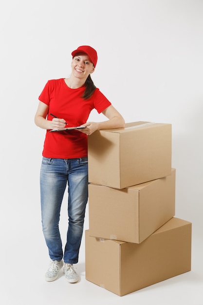 In voller länge von der lieferungsfrau in der roten kappe, t-shirt lokalisiert auf weißem hintergrund. weiblicher kurier, der klemmbrett mit papierdokument hält, leeres leeres blatt auf leeren kartons. paket empfangen.