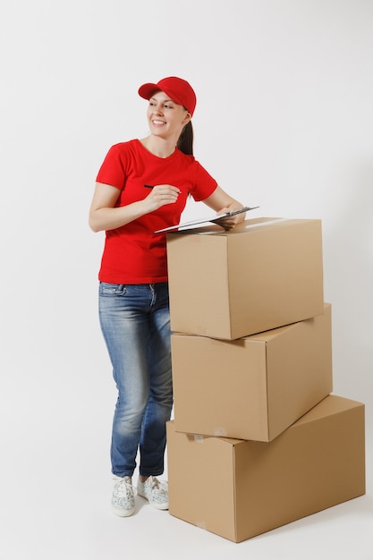 In voller Länge von der Lieferungsfrau in der roten Kappe, T-Shirt lokalisiert auf weißem Hintergrund. Weiblicher Kurier, der Klemmbrett mit Papierdokument hält, leeres leeres Blatt auf leeren Kartons. Paket empfangen.