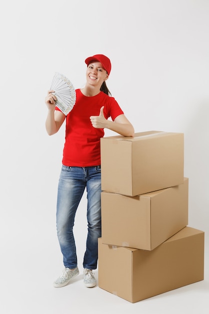 In voller Länge von der Lieferungsfrau in der roten Kappe, T-Shirt lokalisiert auf weißem Hintergrund. Weiblicher Kurier in der Nähe von leeren Kartons, Dollarbündel, Bargeld. Paket empfangen. Platzwerbung kopieren.