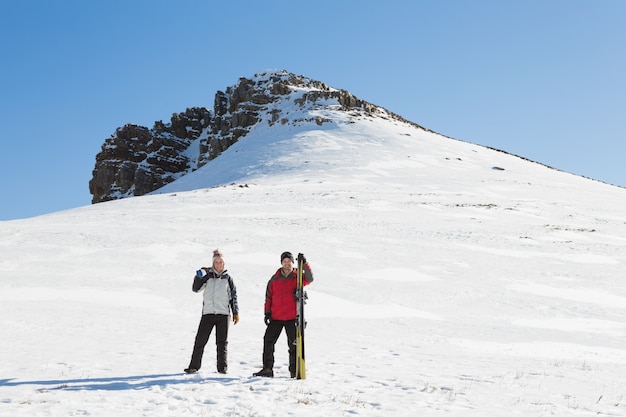 In voller Länge von einem Paar mit den Skiboards, die auf Schnee stehen