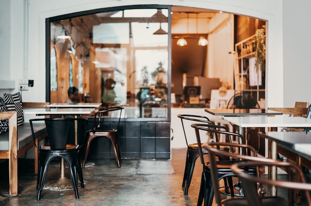 Foto in warmen farben dekorierter kaffee im café lässt es warm aussehen zum ausruhen oder sitzen geeignet die ladenmöbel sind mit braunen eisenstühlen ausgestattet. die tischplatte besteht aus weißem marmor. weiche sitz- und tonregelung