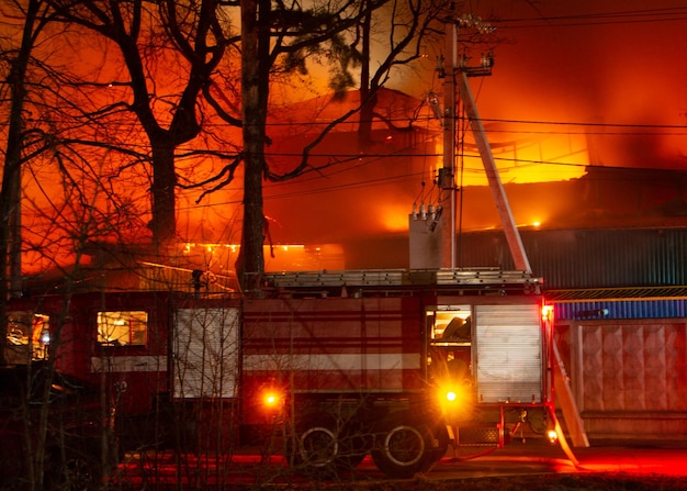 Incêndio no prédio da fábrica à noite. bombeiros tentam apagar o fogo