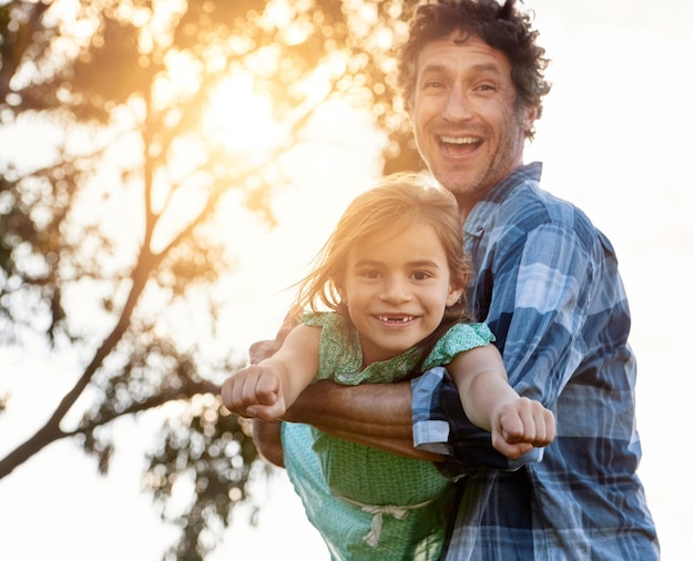 Incentive sua coragem Retrato de um pai feliz carregando sua filha durante um dia divertido ao ar livre