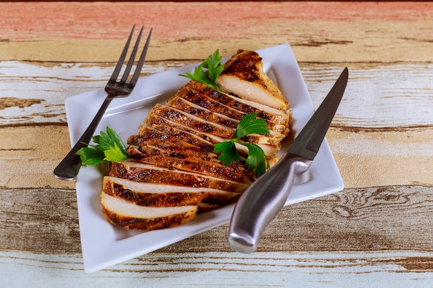 Incisão de frango assado com legumes, em um prato branco