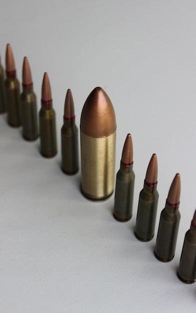 Inclusão e Diversidade Linha de mesmas balas com uma bala grande alinhada isolada em branco
