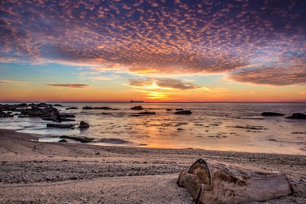 Increíble amanecer de mar con tocón en la playa