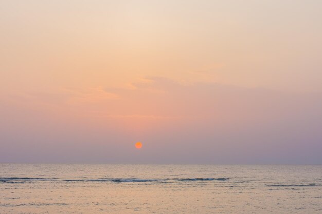 Increíble amanecer con sol naranja cálido y cielo colorido en el mar