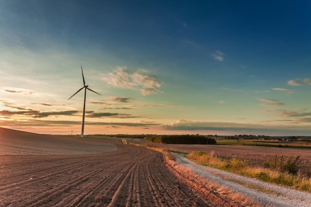 Increíble atardecer en el campo con aerogenerador en otoño