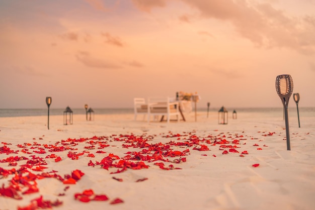 Increíble cena romántica en la playa con velas y flores bajo el cielo del atardecer. romanticismo y amor