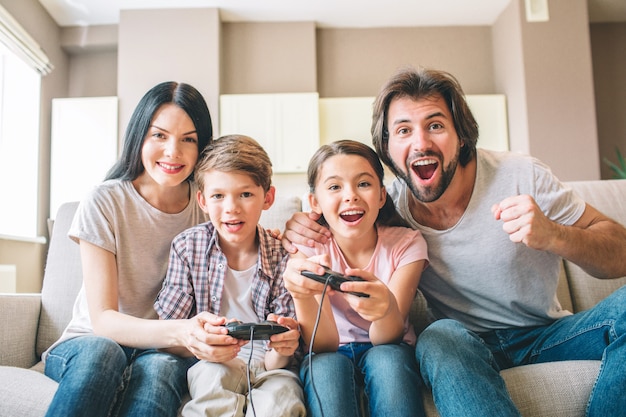 Increíble familia se sienta en el sofá jugando videojuegos