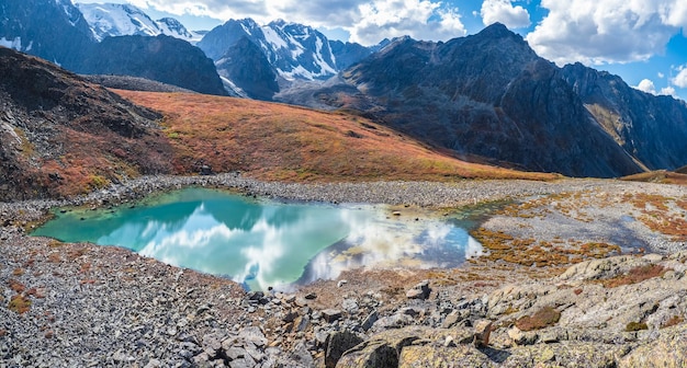 Increíble lago de montaña limpio en un valle de gran altitud Hermosa naturaleza de las montañas de Altai Lago en el valle rocas y nieve Maravilloso día soleado de verano con hermoso paisaje nublado