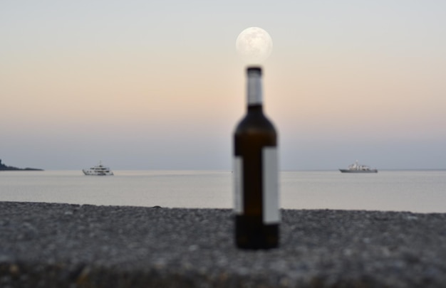 Increíble luna llena sobre el mar y sobre botellas abandonadas en el muelle