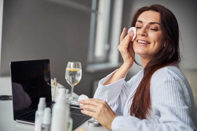 Increíble mujer morena preparando la piel para el maquillaje