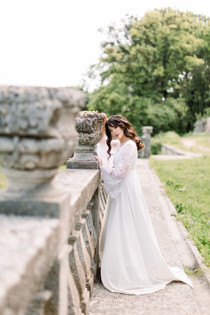 Increíble novia china asiática morena en vestido de novia de lujo, posando en el antiguo castillo