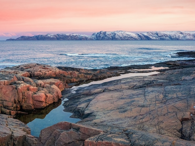 Increíble paisaje de amanecer con cordillera nevada blanca polar de montañas. Maravilloso paisaje de montaña con un desfiladero y un cabo a orillas del mar de Barents. Teriberka