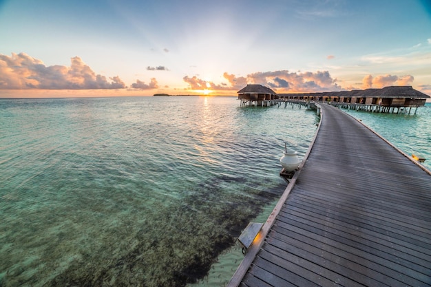 Increíble panorama de puesta de sol en Maldivas. Villas de resort de lujo paisaje marino bahía belleza reflejo de la superficie del mar