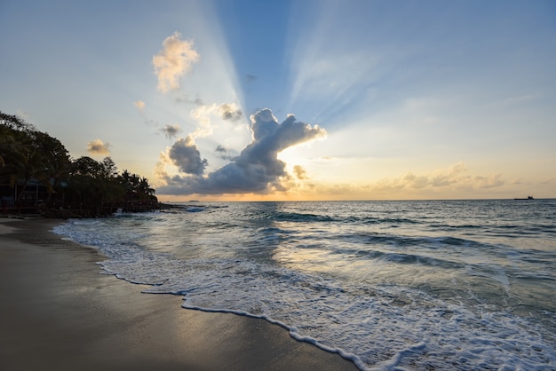 Foto increíble playa de arena tropical con la silueta de la playa tropical - amanecer o atardecer mar cielo dramático