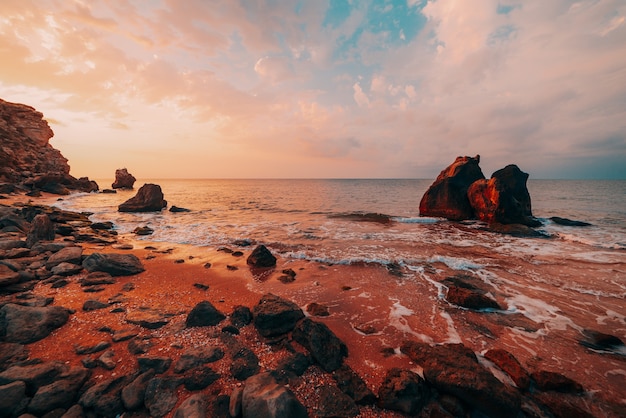 Increíble puesta de sol en el mar, belleza de la naturaleza. Vista panorámica del mar, costa rocosa y playa de arena, cielo dorado y sol