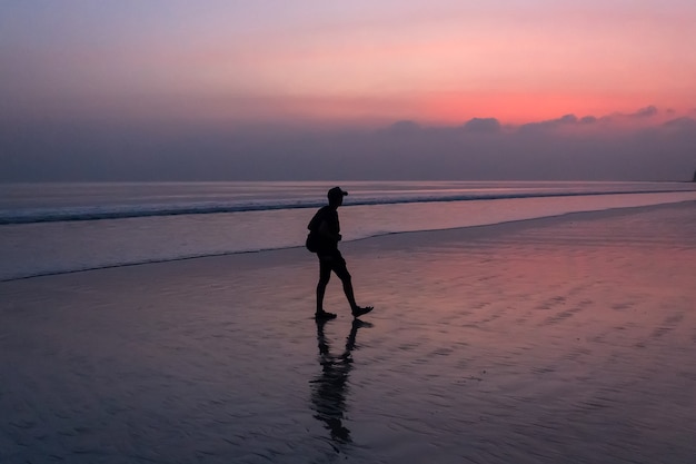 Increíble puesta de sol de mar con reflejo. Hombre solitario. Un mar al atardecer colorido, hombre de pie observando la belleza de la naturaleza. El cielo y el hombre se reflejan en un charco de agua frente al mar.