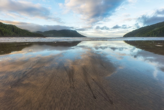 Foto increíble reflexión sobre la playa de la bahía de san josef en el parque provincial cape scott en la isla de vancouver, columbia británica, canadá.