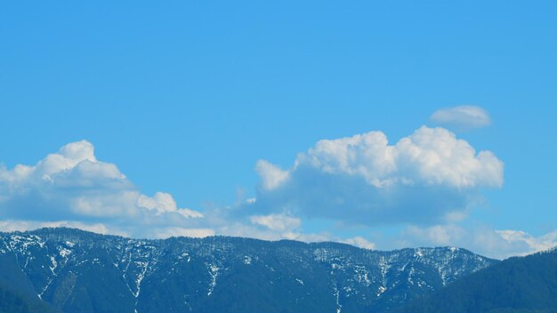 Foto increíble topografía del paisaje cordillera congelada con nieve y nubes en un día de cielo azul brillante