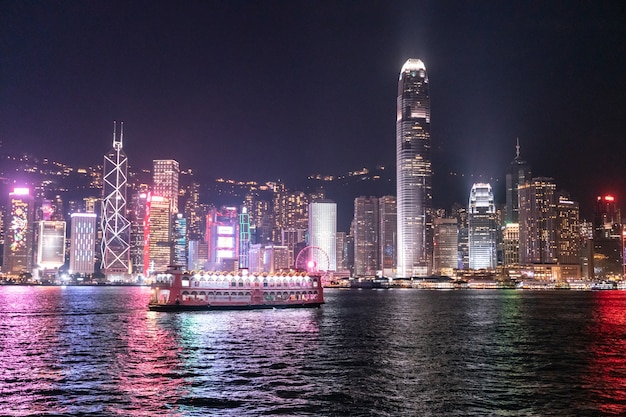 Foto la increíble vista del paisaje urbano nocturno de luces sobre el agua en el puerto de victoria en hong kong